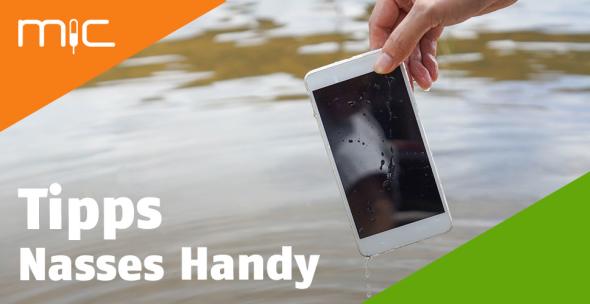 Eine Frau hält ein nasses Handy über einem Gewässer.