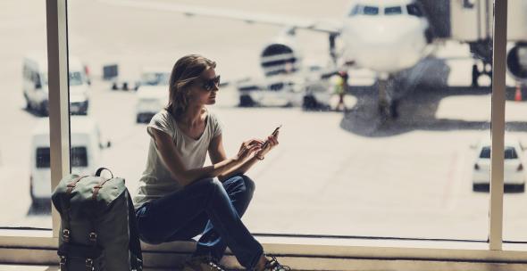 Young woman using smartphone in the airport, travel, vacations and active lifestyle concept